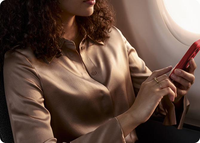 Woman seated in airplane window seat using cell phone
