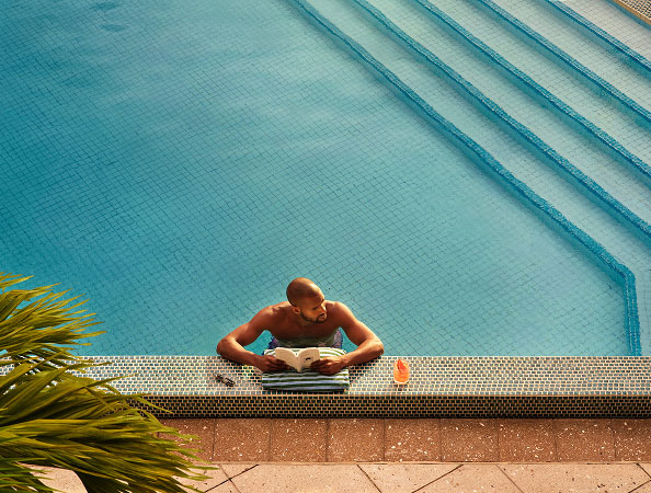 A man reads a book from a pool