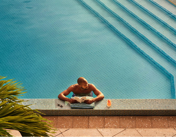 A man reads a book from a pool