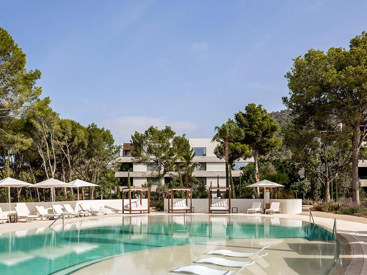 Outdoor pool surrounded by trees at Kimpton Aysla Mallorca
