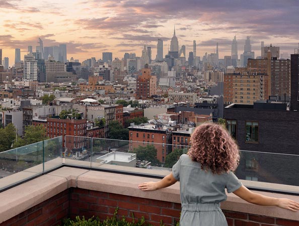 Woman looking over balcony at Manhattan skyline