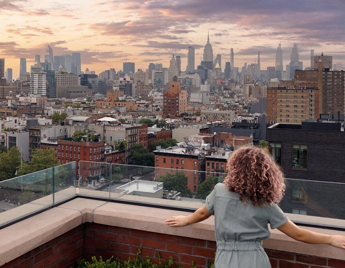 Woman looking over balcony at Manhattan skyline