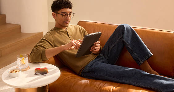 Man laying on a couch scrolling on a tablet