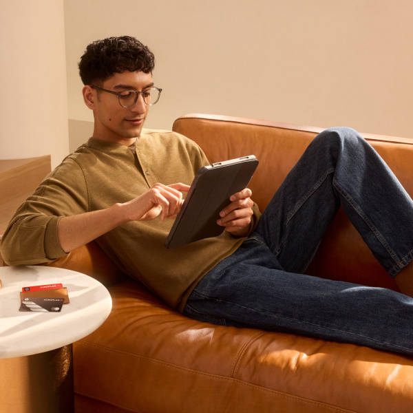 Man laying on a couch scrolling on a tablet