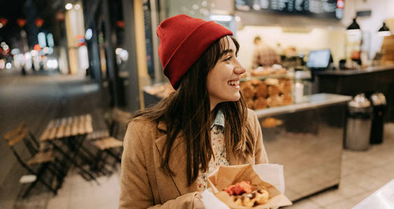 Woman smiling with a snack purchased from an outdoor stall