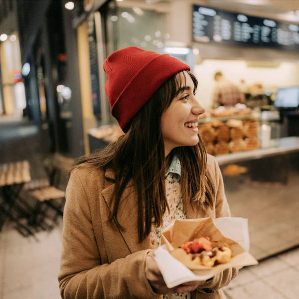 Woman smiling with a snack purchased from an outdoor stall