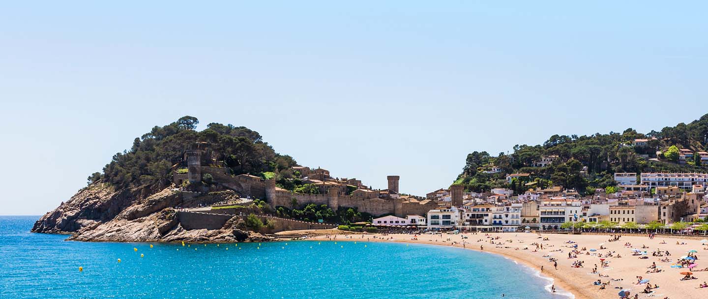 Coastal town in Catalonia, Spain with a beach and hillside buildings.