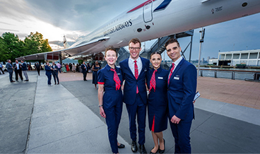 Group standing on an airport tarmac beside an aircraft