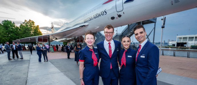 Group standing on an airport tarmac beside an aircraft