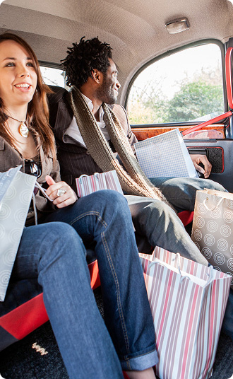 Passengers seated in the backseat of a vehiclesurrounded by shopping bags.