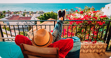 Traveler relaxing on a balcony overlooking a coastal town in Spain.