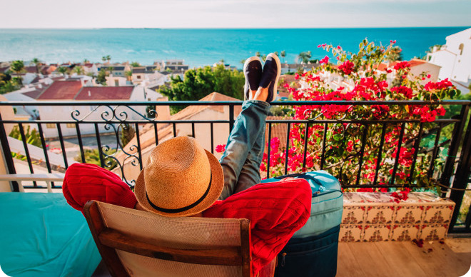 Traveler relaxing on a balcony overlooking a coastal town in Spain.