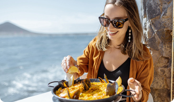 Traveler eating paella at a seaside restaurant in Spain.