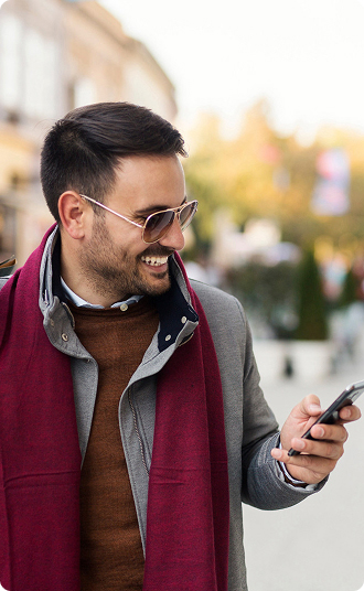 Person wearing a coat and scarf looking at a smartphone outdoors