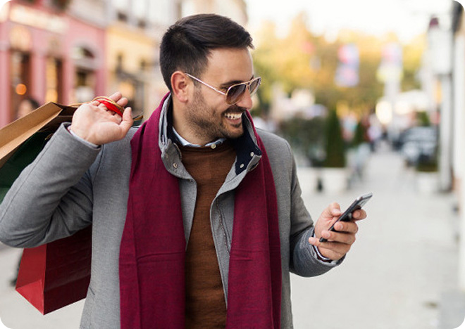 Person wearing a coat and scarf looking at a smartphone outdoors