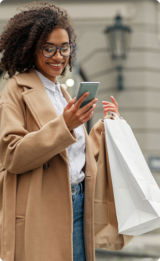 Traveler checking a mobile phone while walking on a city street.