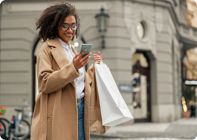 Traveler checking a mobile phone while walking on a city street.