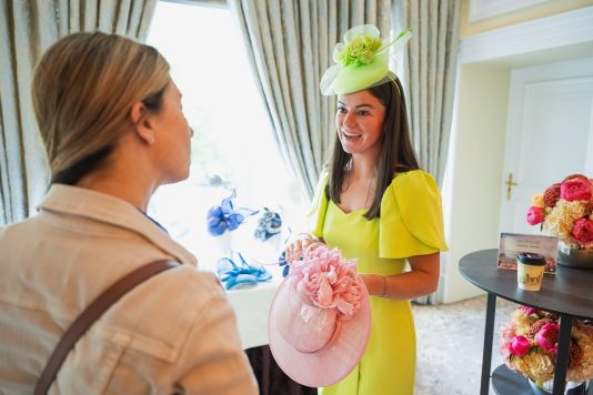 Two guests chatting one wearing yellow fasinator