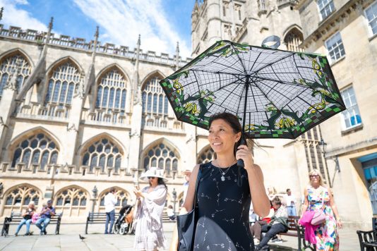 Guest carrying decorative parasol near Bath Abbey