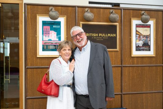 Guests posing beside British Pullman train