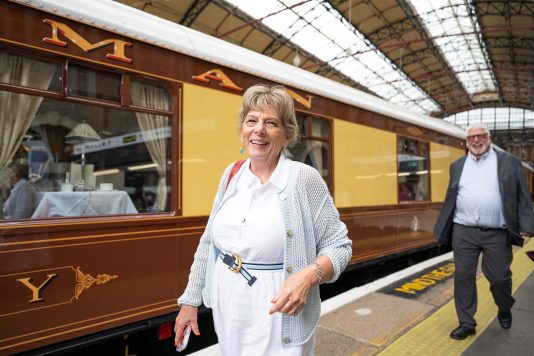 Guest walking beside British Pullman train