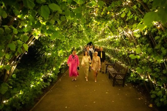 Guests walking through illuminated garden arbor