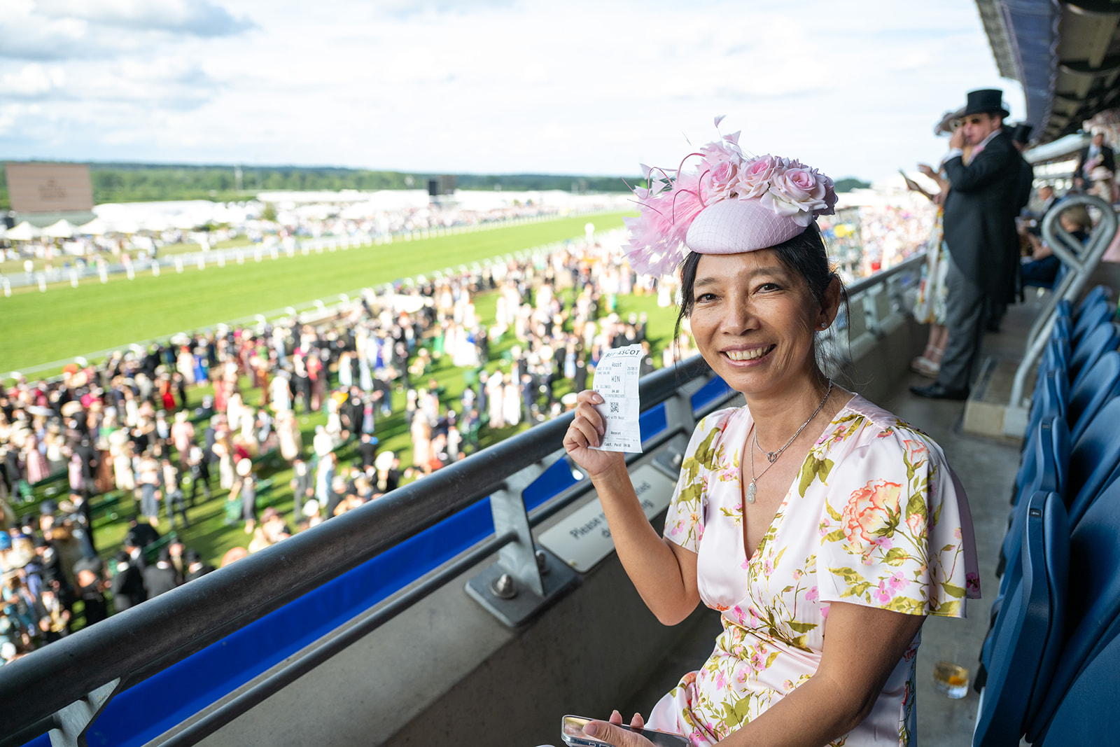 Attendee in pink floral fascinator overlooking track