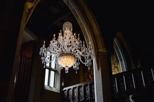 Crystal chandelier hanging in vaulted interior.