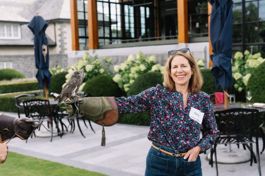Attendee holding bird of prey on gloved arm.