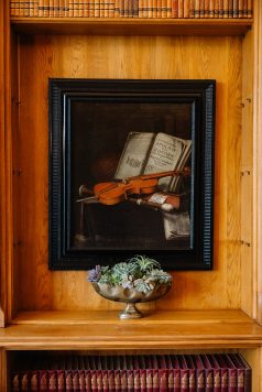 Framed artwork of violin on wooden wall.