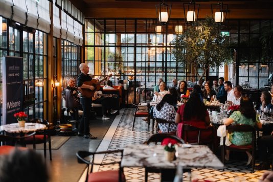 Wide view of dinner in glass room.