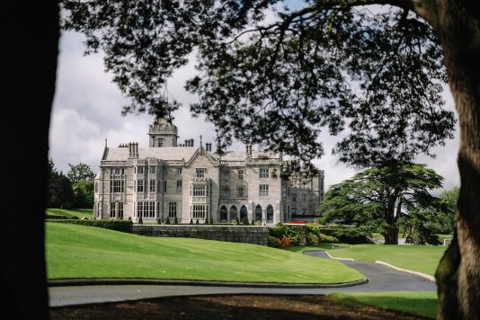 Adare Manor framed by trees and driveway.