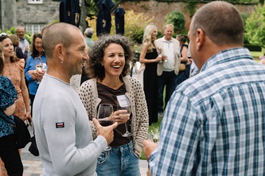 Guests chatting and holding drinks outdoors.