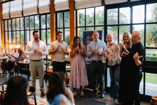 Group of guests standing with drinks indoors.