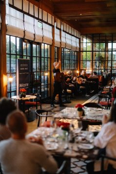 Speaker addressing guests in glass dining room.
