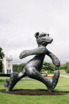 Garden statue in black and white with manor behind.