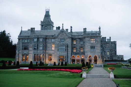 Adare Manor exterior at dusk with lights on.