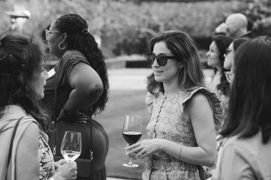 Attendees conversing outdoors in black and white.