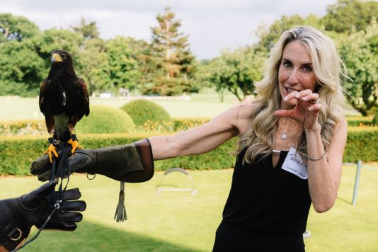 Attendee holding bird of prey outdoors.