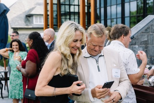 Guests looking at phone together outdoors.
