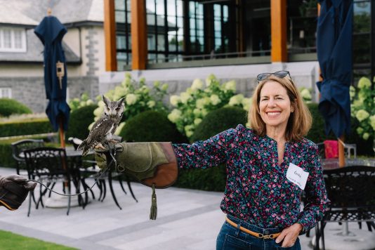 Attendee holding bird of prey outdoors.