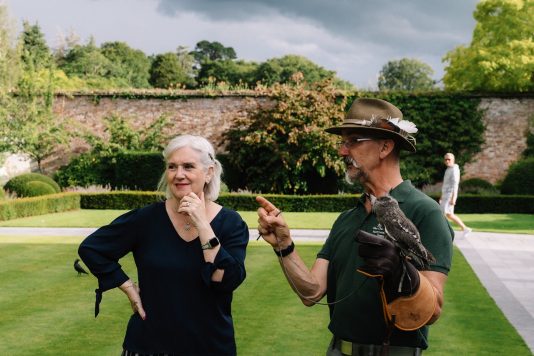 Falconer speaking with attendee on lawn.