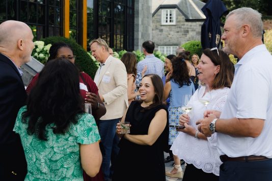 Guests mingling outside manor building.