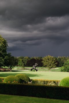 Bronze statue on the green under dark sky.