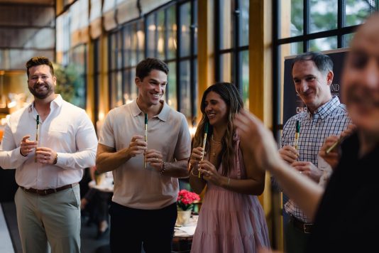 Attendees standing together holding drinks indoors.