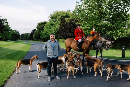 Rider with hounds gathered on estate road.