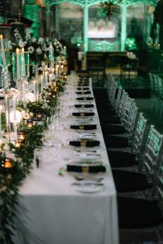 Long banquet table with candles and greenery.