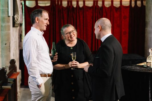 Three guests speaking during a reception.