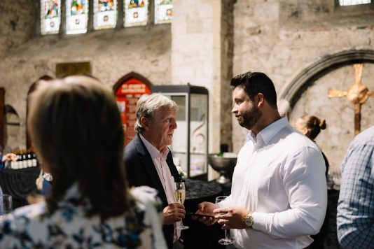 Guests conversing inside stone hall during event.