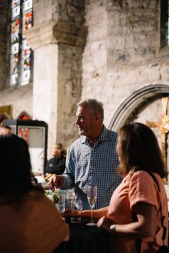 Guests mingling in the foreground of a stone archway.